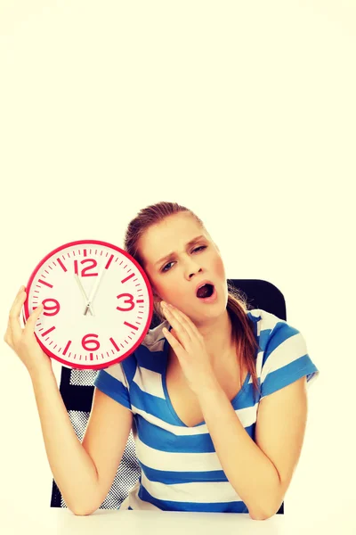 Tired yawning teenage woman holding clock — Stock Photo, Image