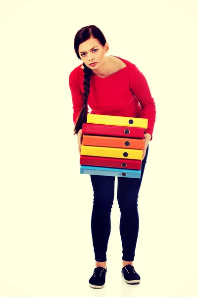Уставшая молодая женщина держит тяжелые папки — стоковое фото