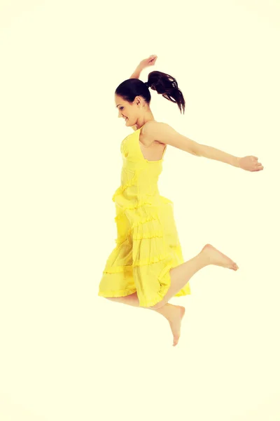 Beautiful woman jumping in yellow dress. — Stock Photo, Image