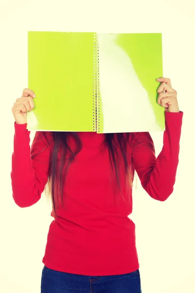 Woman hiding her face behind a notebook. — Stock Photo, Image