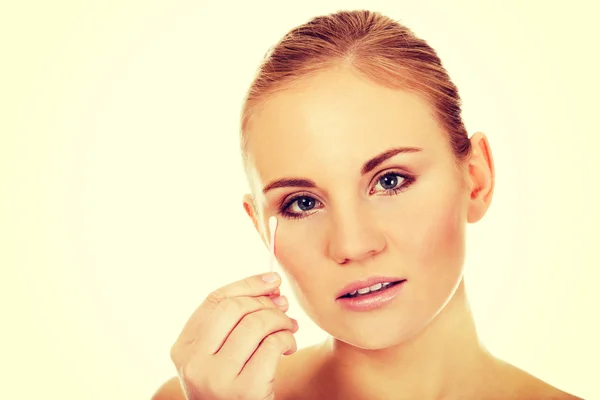 Jonge vrouw verwijderen van oog make-up met wattenstaafje — Stockfoto