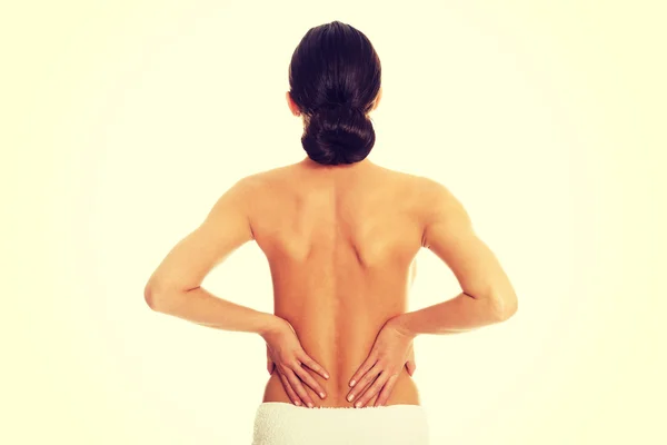 Женщина, завернутая в полотенце с болью в спине — стоковое фото