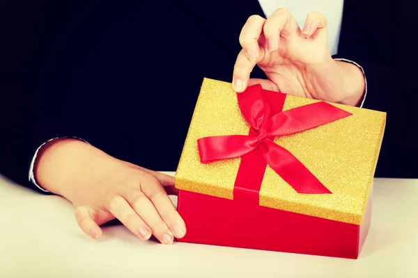 Business woman opens a gift box behind the desk — Stock Photo, Image