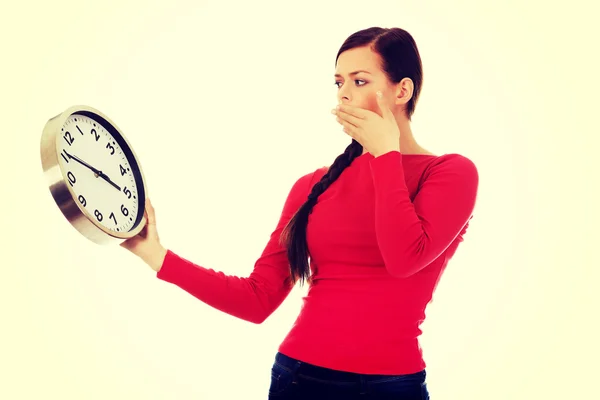 Young yawning woman holding a clock — Stock Photo, Image