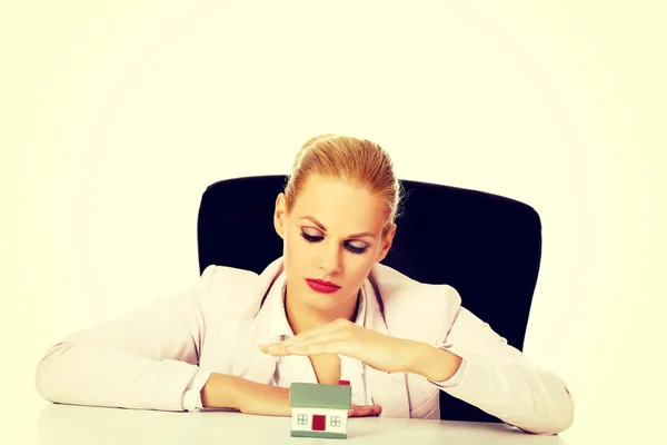 Mulher de negócios sentada atrás da mesa com modelo de casa — Fotografia de Stock