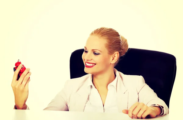 Szczęśliwy biznes kobieta siedzi za biurkiem i trzymając budzik — Zdjęcie stockowe