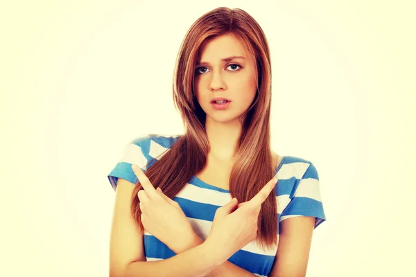 Confused teenage woman pointing in two different directions — Stock Photo, Image
