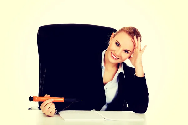 机の後ろに座って大きなペンで何かを書くビジネス女性 — ストック写真