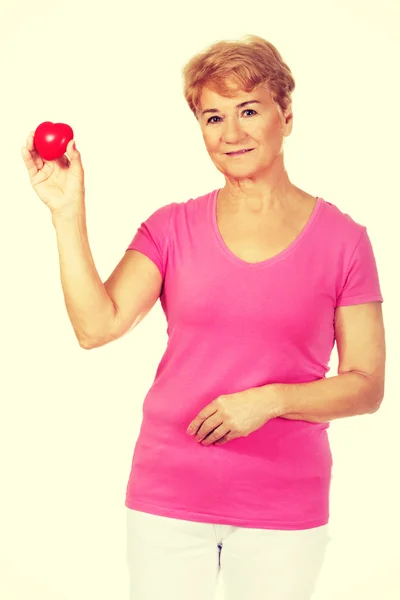 Oude lachende vrouw met rode speelgoed hart — Stockfoto