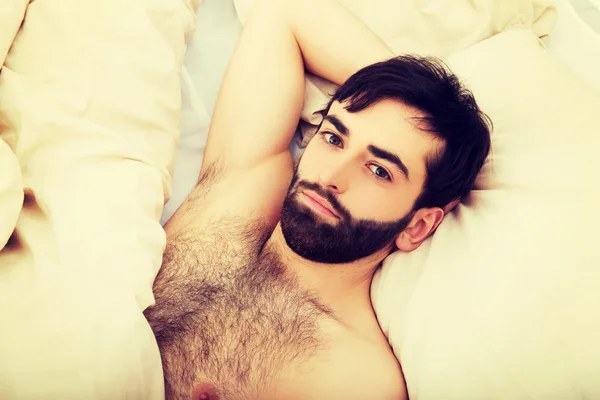 Young muscular man lying in bed. — Stock Photo, Image