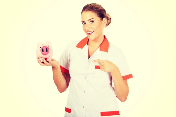 Fiatal gyönyörű női orvos vagy nővér kezében egy malacpersely — Stock Fotó