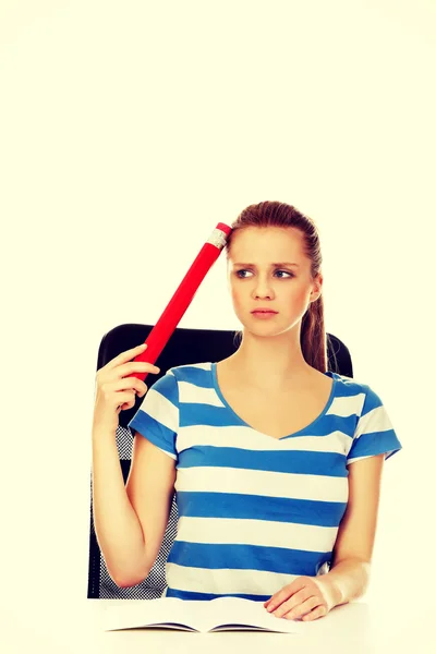 Adolescente donna facendo i compiti e tenendo penna enorme — Foto Stock