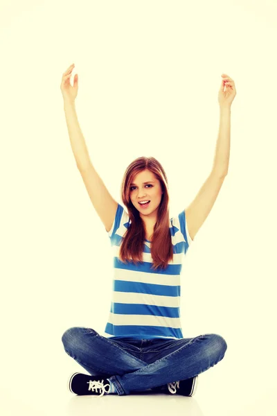 Happy teenage woman sitting with arms up — Stock Photo, Image