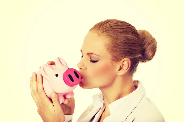 Ung affärskvinna kysser en piggybank — Stockfoto