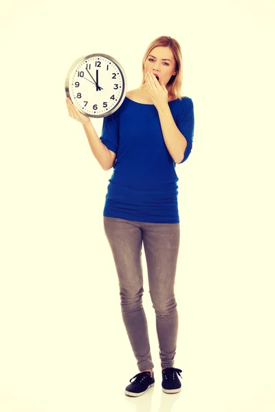 Mladá zející žena drží hodiny — Stock fotografie
