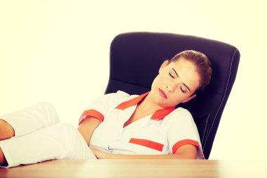 Genç yorgun kadın doktor ayakları masaya yatıyor