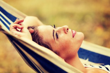 Genç sarışın kadın hamakta dinleniyor.
