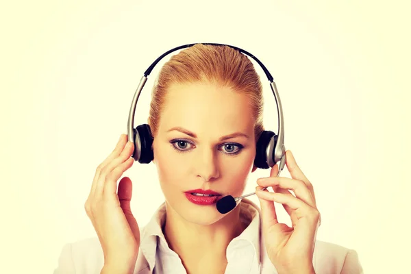 Mujer joven operador de línea de ayuda está tratando de escuchar algo a través de los auriculares —  Fotos de Stock