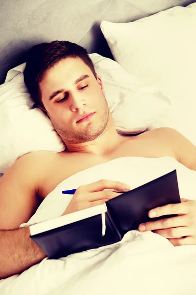 Mann schreibt eine Notiz in sein Bett. — Stockfoto