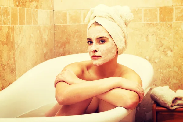 Woman sitting in bath with face mask — Stock Photo, Image