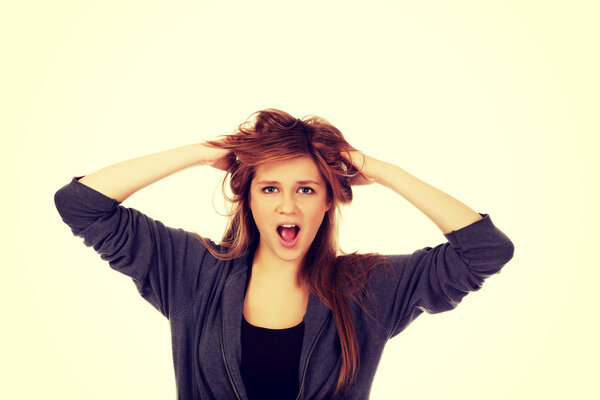 Молодая удивленная женщина держит руки внутри волос
