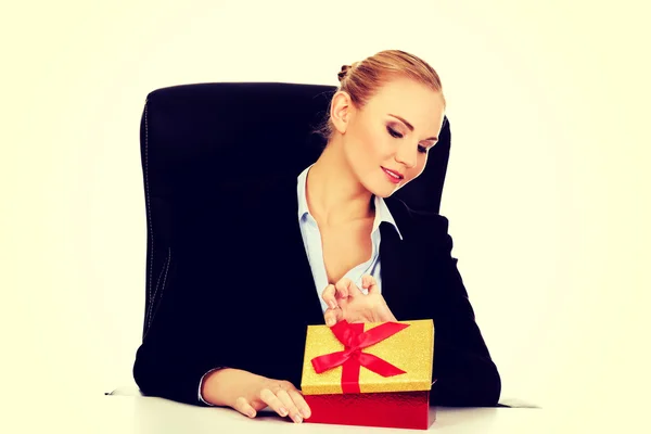 Sorriso mulher de negócios abre uma caixa de presente atrás da mesa — Fotografia de Stock