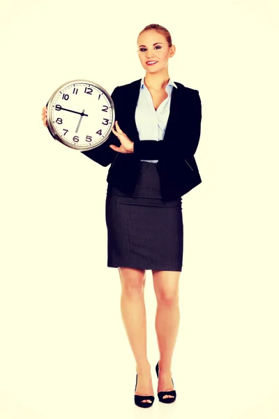 Sonriente joven mujer de negocios sosteniendo reloj de oficina —  Fotos de Stock