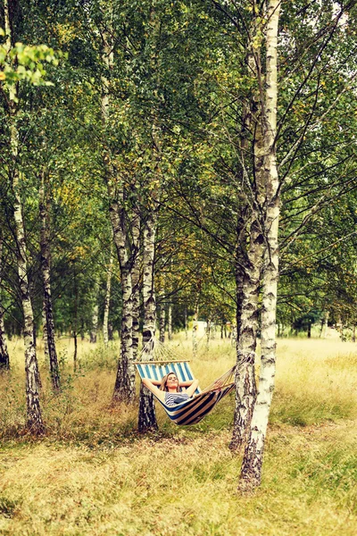 Ung kvinna med tablett på hängmattan — Stockfoto