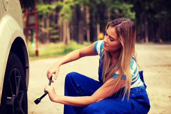 Female mechanic changing tire with wheel wrench — Stock Photo, Image