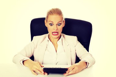 Hesap makinesi ile masanın arkasında oturan şok iş kadını