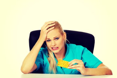 Şok ve korkmuş kadın hemşire ya da doktor arkasında oturan Resepsiyon ve paket hap holding