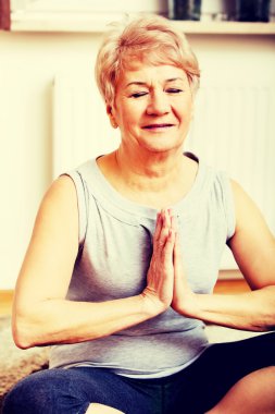 Üst düzey kadın oturma odasında yoga yapıyor.