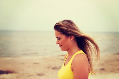 Kumsalda ayakta duran yorgun kadın.