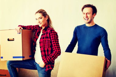 Mutlu çift yeni evinde karton kutular taşıyor.
