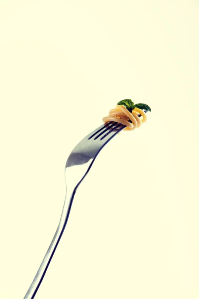 Pasta on fork tines, garnished with basil leaf — Stock Photo, Image