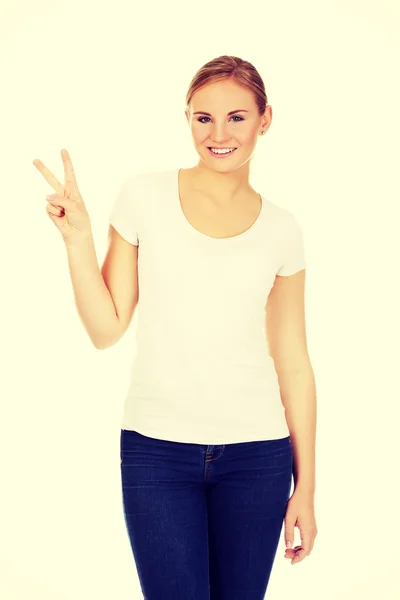 Gülümseyen genç kadın zafer işareti gösterilen — Stok fotoğraf
