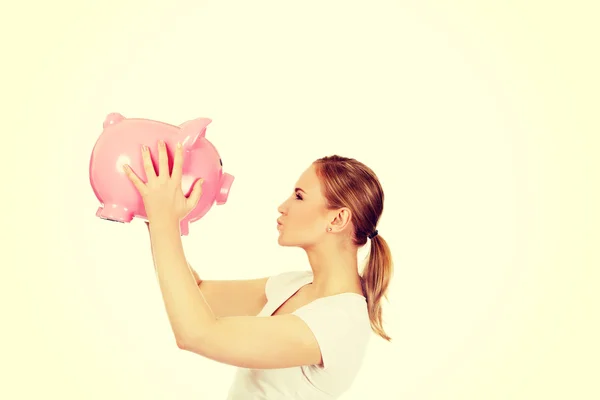 Happy young woman kissing a piggybank — Stock Photo, Image