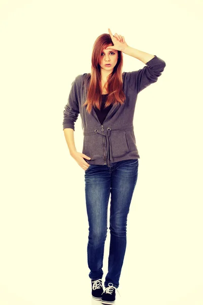 Teenage woman makes loser sign on her forehead — Stock Photo, Image