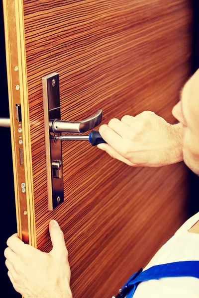 Молодой человек чинит дверь отверткой — стоковое фото