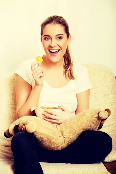 Mujer joven viendo la televisión y comiendo patatas fritas —  Fotos de Stock