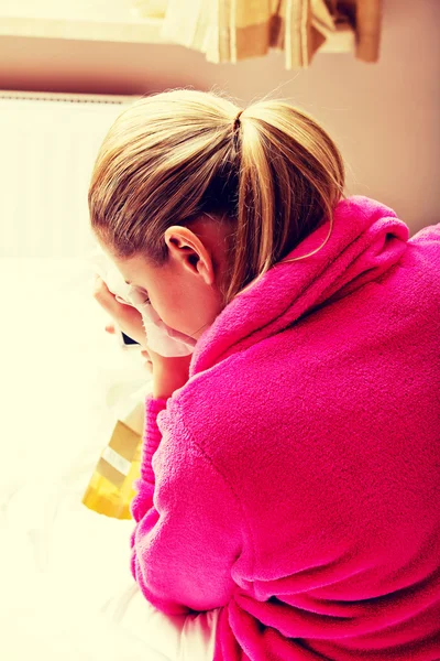 Young woman sitting on the bed crying and drinking whiskey — Stock Photo, Image