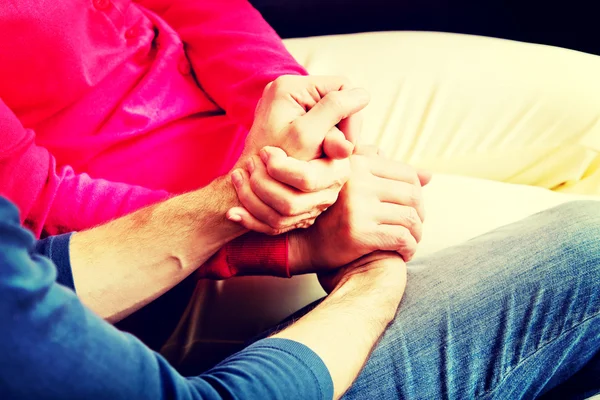 Mother and son sitting on couch and holding hands — Stock Photo, Image