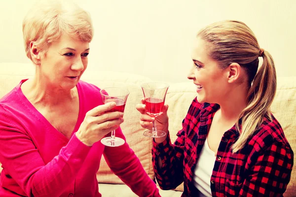 Mulher sênior feliz com filha ou neta bebendo vinho — Fotografia de Stock