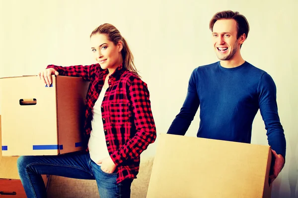 Happy couple carrying cardboard boxes in new home — Stock Photo, Image