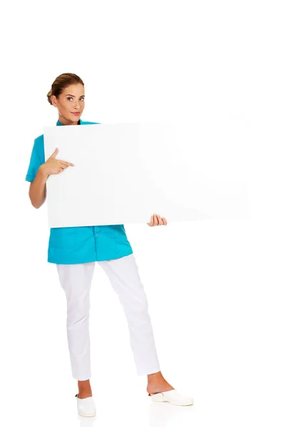 Young female doctor or nurse holding empty banner — Stock Photo, Image