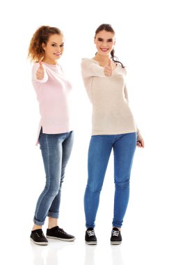 İki genç mutlu kadın başparmak gösterilmesini