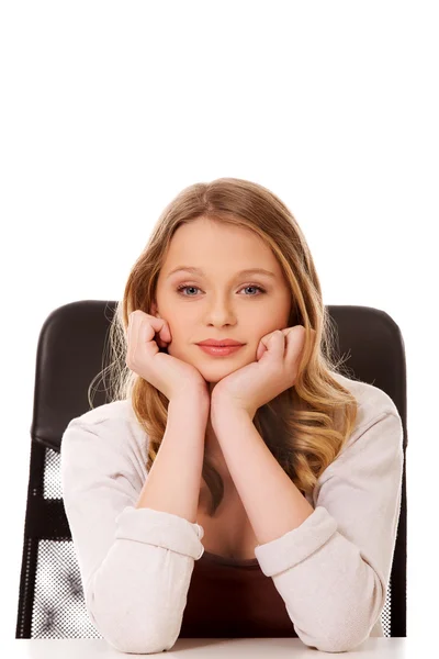 Młoda kobieta szczęśliwa siedzi przy biurku — Zdjęcie stockowe
