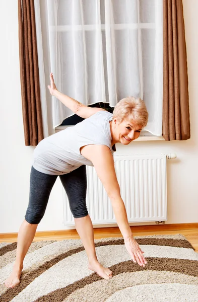 Senior woman doing yoga in living room — Stock Photo, Image