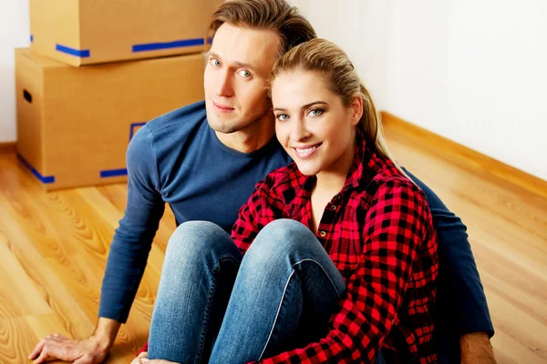 Pasangan bahagia Yougn duduk di lantai di rumah baru — Stok Foto