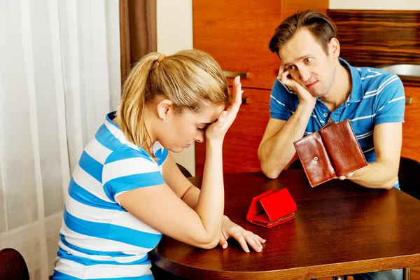 Worried couple sitting at the table with empty wallets — Stock Photo, Image